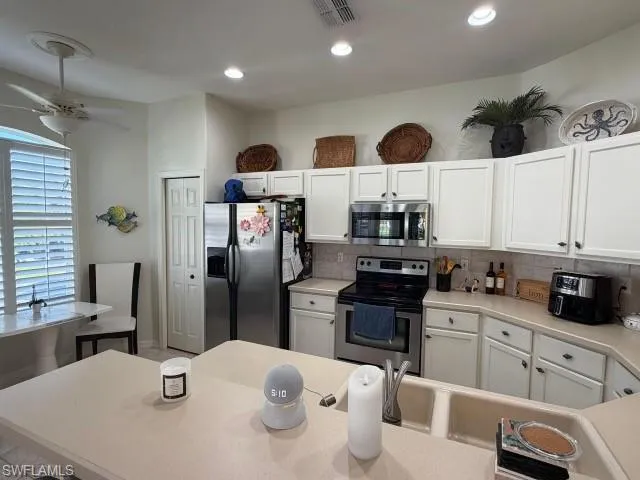 Kitchen featuring light countertops, white cabinetry, stainless steel appliances, tasteful backsplash, and recessed lighting