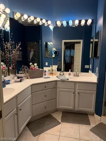 Full bathroom featuring double vanity, a shower stall, and light tile patterned flooring