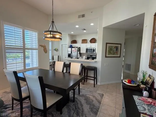 Dining space with light tile patterned floors and recessed lighting