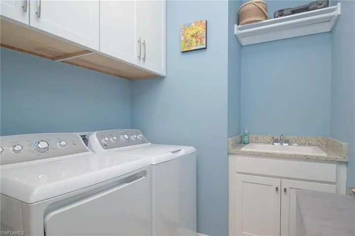 Laundry area featuring cabinets, washer and clothes dryer, and sink