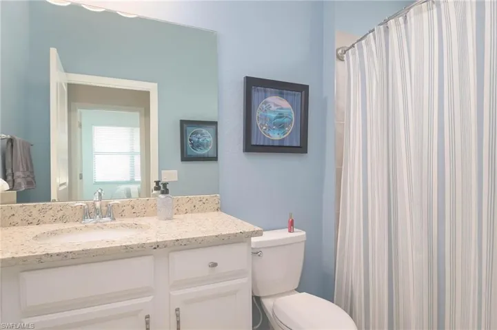 Bathroom with curtained shower, vanity, and toilet