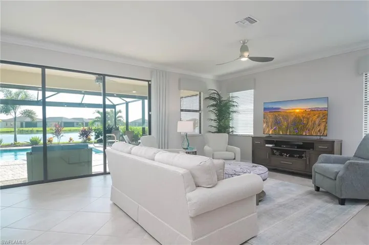 Tiled living room featuring ceiling fan and ornamental molding