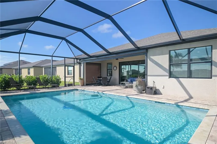 View of pool with glass enclosure and a patio area