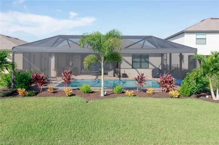 Back of house with a yard and a lanai