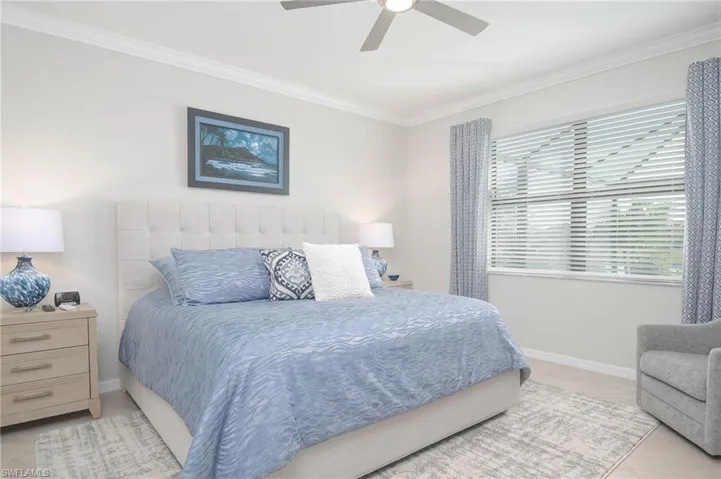 Tiled bedroom with ornamental molding and ceiling fan