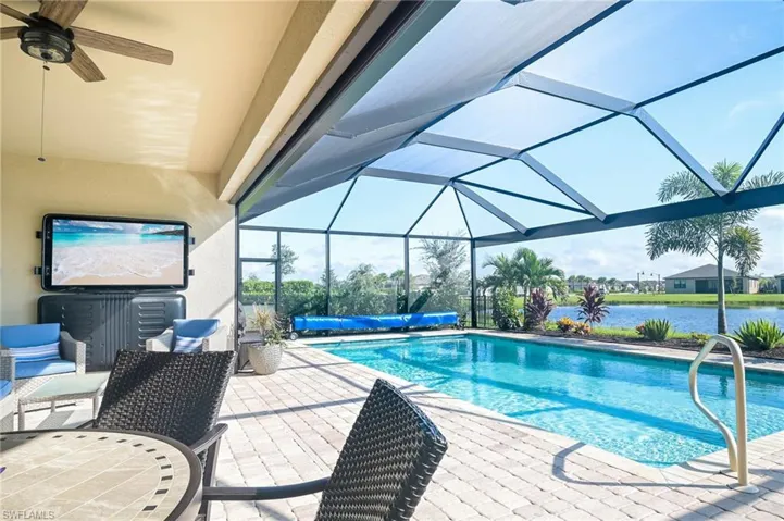 View of swimming pool featuring a water view, a lanai, ceiling fan, and a patio area