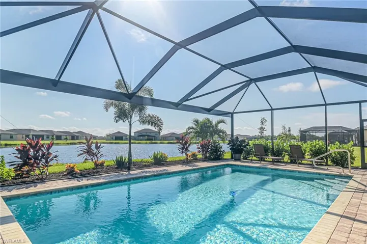 View of swimming pool featuring glass enclosure and a water view