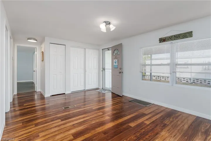 Unfurnished bedroom featuring visible vents, dark wood finished floors, baseboards, and two closets