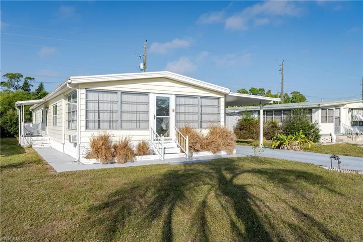 Front view of property featuring entry steps, a carport, and a front yard