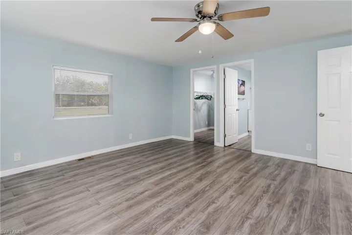 Unfurnished bedroom with visible vents, baseboards, ceiling fan, and wood finished floors