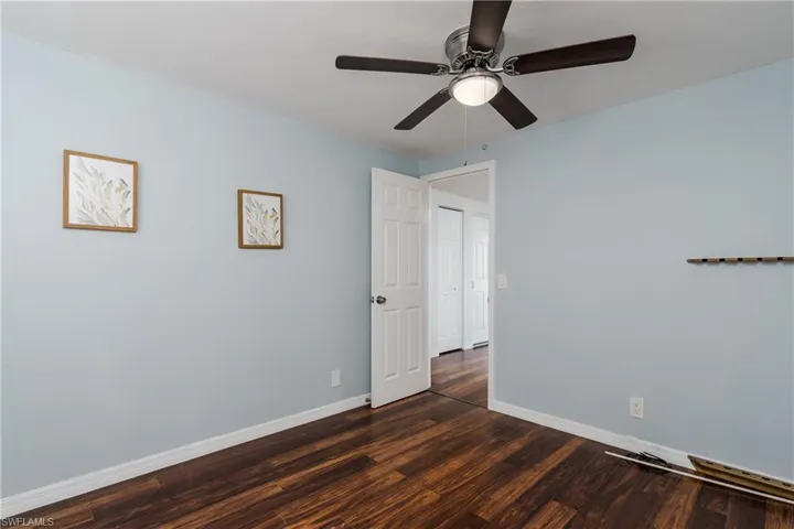 Unfurnished bedroom with dark wood-style floors, baseboards, and a ceiling fan