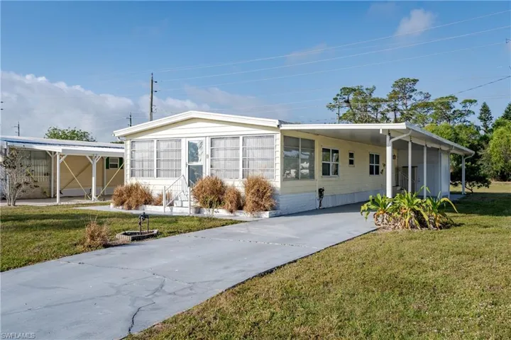 Manufactured / mobile home featuring a carport, a front yard, concrete driveway, and entry steps