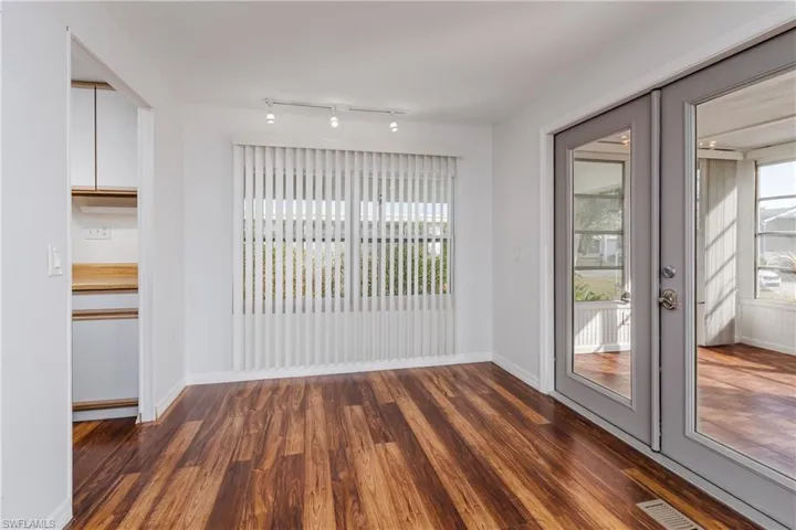 Spare room featuring french doors, visible vents, baseboards, and dark wood-style flooring