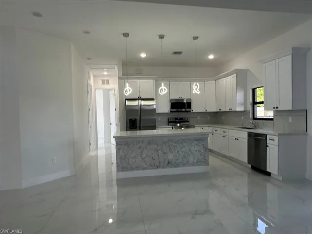 Kitchen featuring visible vents, marble finish floor, white cabinetry, stainless steel appliances, and decorative backsplash