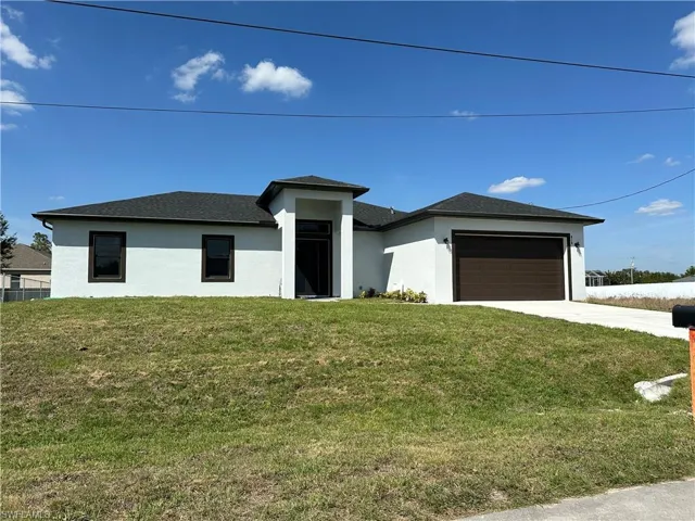 Prairie-style home with stucco siding, an attached garage, concrete driveway, and a front lawn