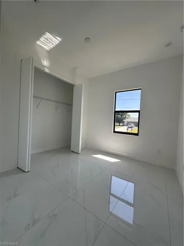 Unfurnished bedroom with a closet and marble finish floor