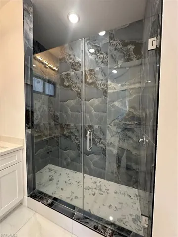 Full bathroom featuring tile patterned flooring, a shower stall, and vanity
