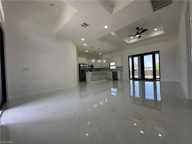 Unfurnished living room with visible vents, marble finish floor, and a tray ceiling