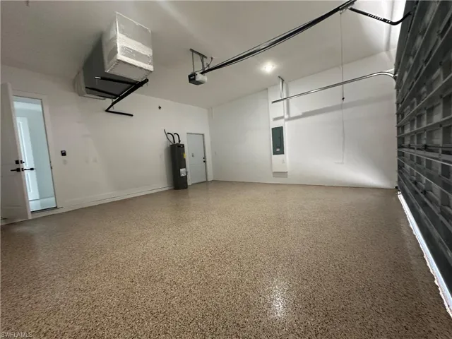 Garage with electric panel, a garage door opener, and water heater