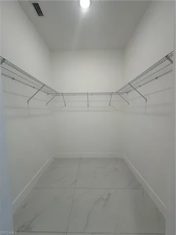 Spacious closet with visible vents and marble finish floor
