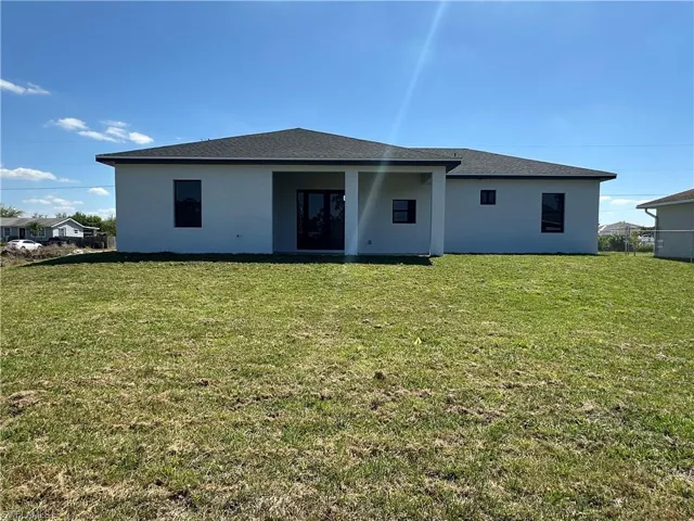 Back of house featuring a lawn and stucco siding