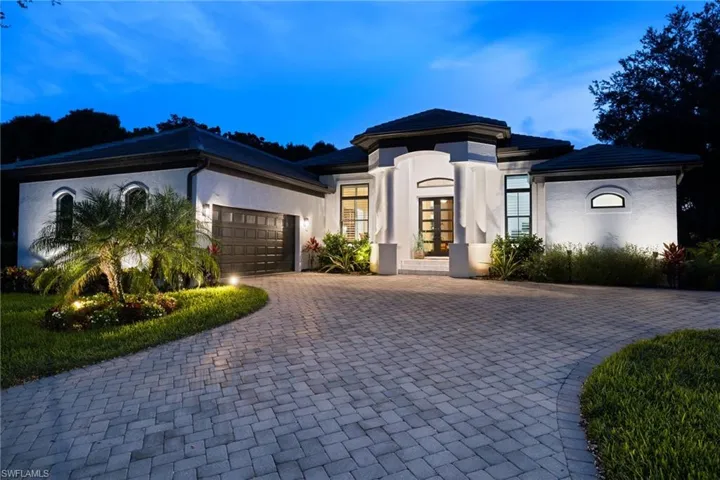 View of front facade with french doors, an attached garage, stucco siding, and decorative driveway