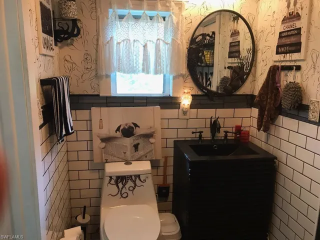 Bathroom featuring tile walls, toilet, and sink