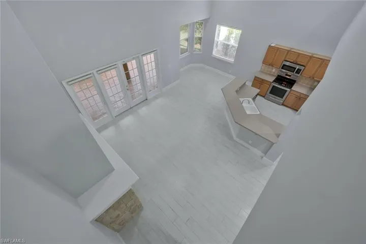 Living room featuring baseboards, a towering ceiling, and light wood-type flooring