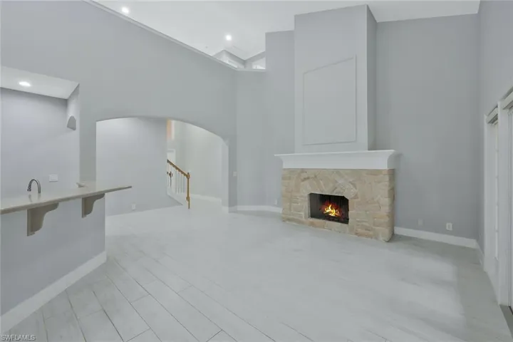 Living area featuring baseboards, a fireplace, arched walkways, and a towering ceiling