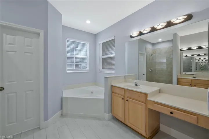 Full bathroom featuring baseboards, tiled shower, vanity, and a garden tub