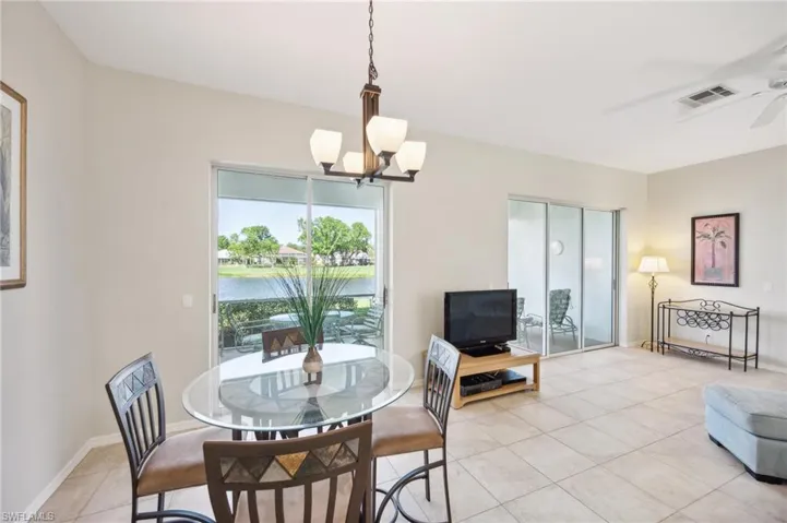 Tiled dining space with ceiling fan with notable chandelier