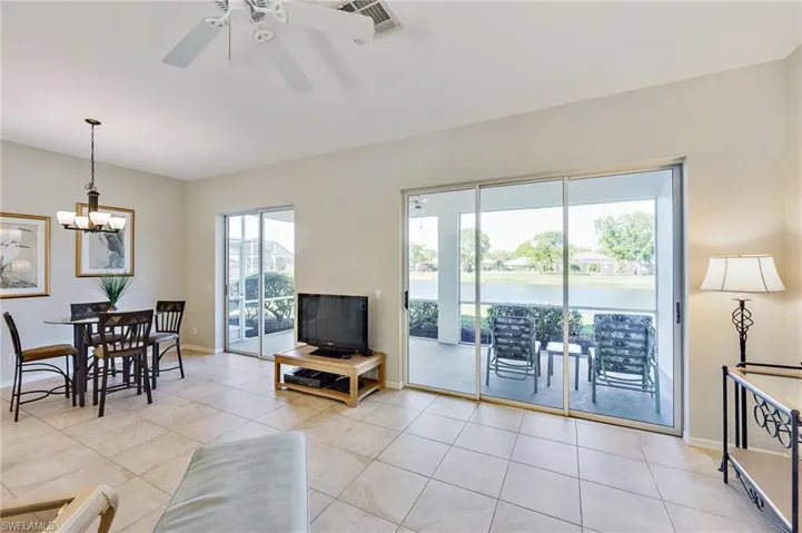 Tiled living room featuring ceiling fan with notable chandelier and a wealth of natural light
