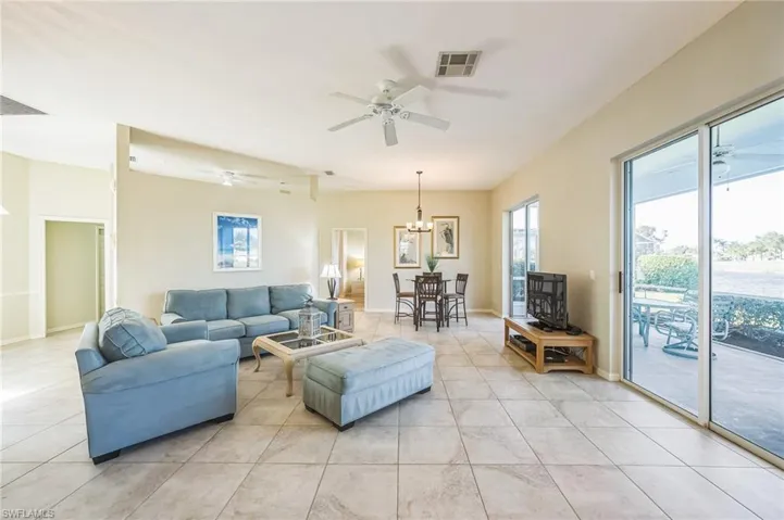 Tiled living room with ceiling fan with notable chandelier