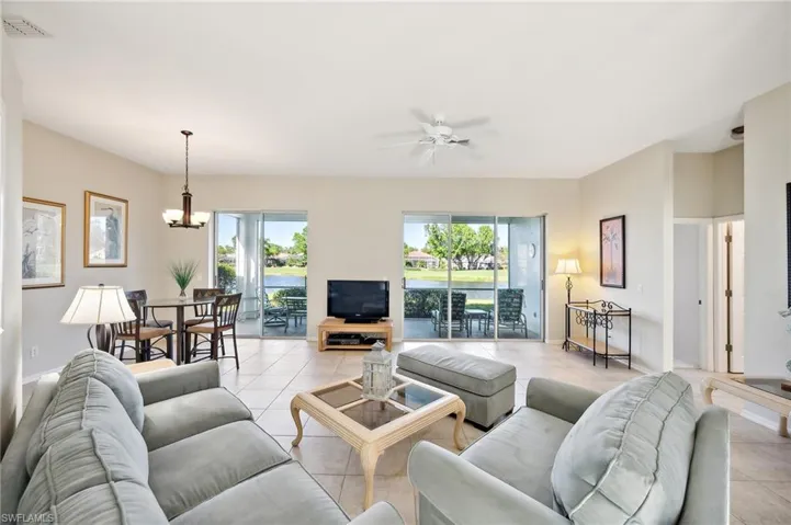 Living room with light tile patterned floors and ceiling fan with notable chandelier