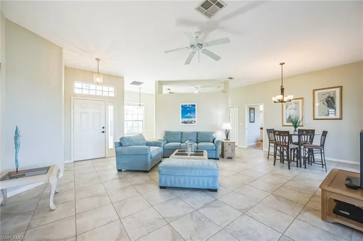 Tiled living room featuring ceiling fan with notable chandelier