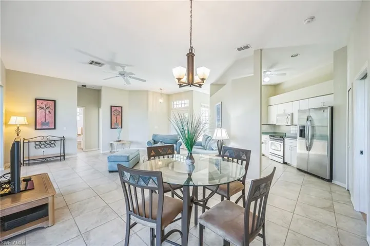 Dining space with ceiling fan with notable chandelier and light tile patterned floors