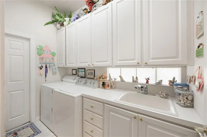 Laundry room featuring washing machine and clothes dryer, cabinet space, and light tile patterned flooring