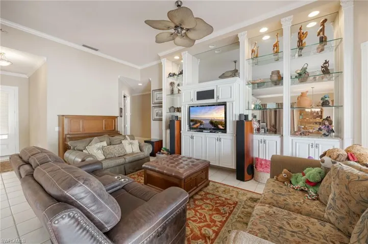 Living room featuring light tile patterned floors, a ceiling fan, and ornamental molding