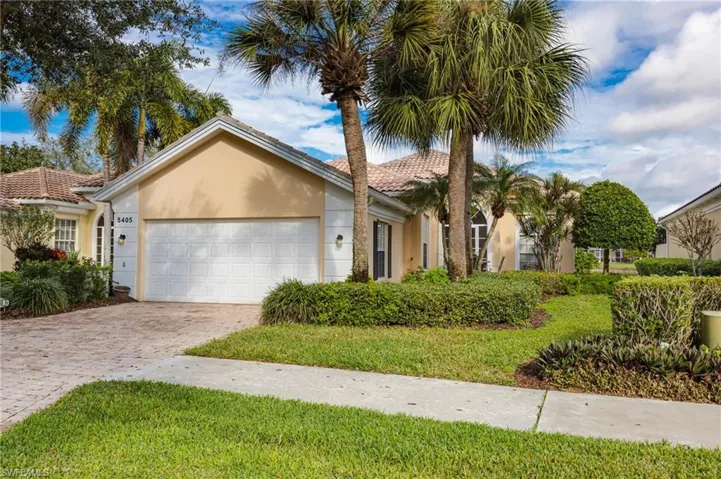 View of front facade featuring stucco siding, decorative driveway, a garage, and a front lawn