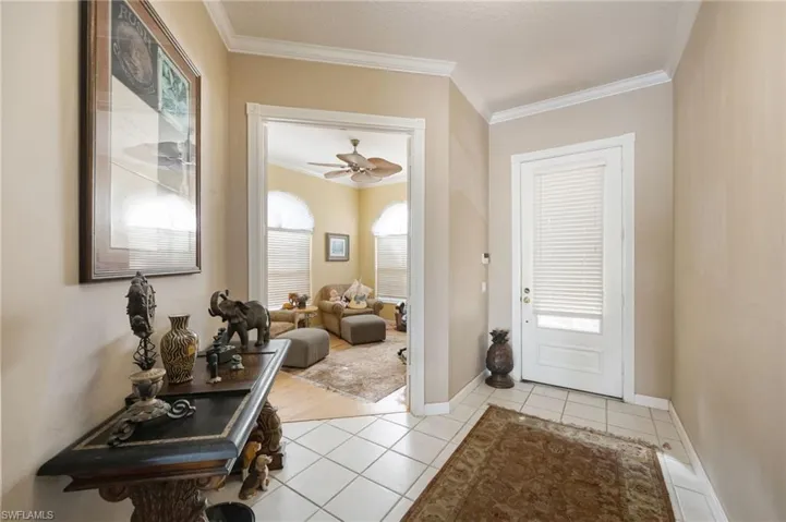 Entrance foyer with crown molding, light tile patterned flooring, and ceiling fan
