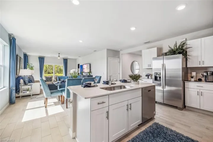 Kitchen with appliances with stainless steel finishes, a sink, light wood-type flooring, white cabinets, and recessed lighting