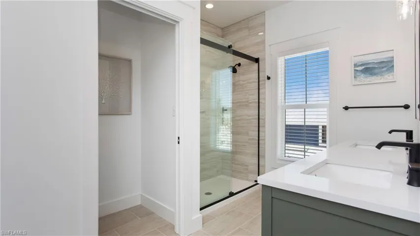 Bathroom featuring a shower stall, double vanity, and recessed lighting