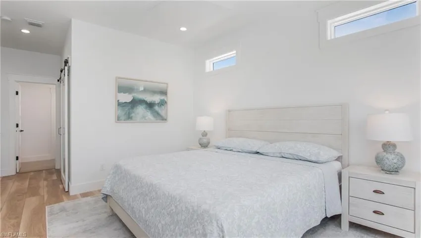 Bedroom with light wood-type flooring, a barn door, and recessed lighting