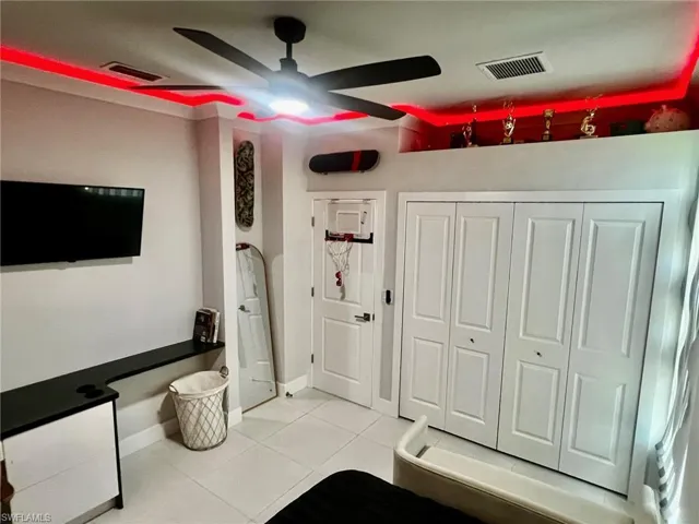 Exercise area featuring light tile patterned floors and a ceiling fan