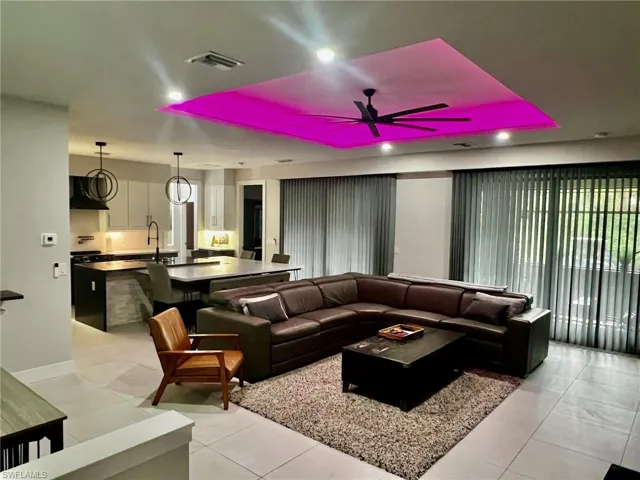 Living room with a ceiling fan, light tile patterned floors, and a raised ceiling