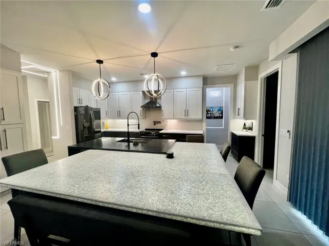 Kitchen featuring a breakfast bar, light tile patterned floors, white cabinets, recessed lighting, and a spacious island