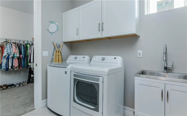Laundry room with cabinet space, washing machine and clothes dryer, and light colored carpet
