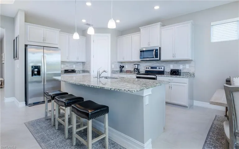 Kitchen with appliances with stainless steel finishes, white cabinetry, a kitchen breakfast bar, backsplash, and recessed lighting