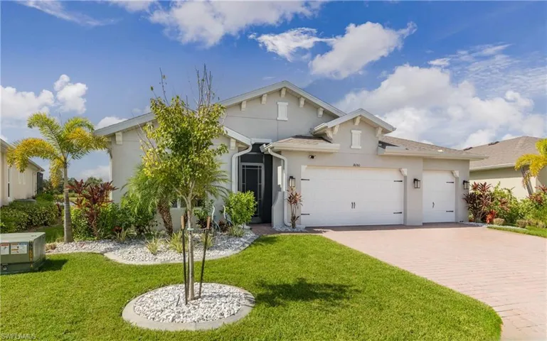 View of front facade featuring stucco siding, decorative driveway, a garage, and a front lawn