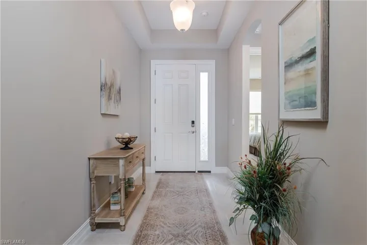 Entryway featuring light tile patterned floors, arched walkways, and a tray ceiling